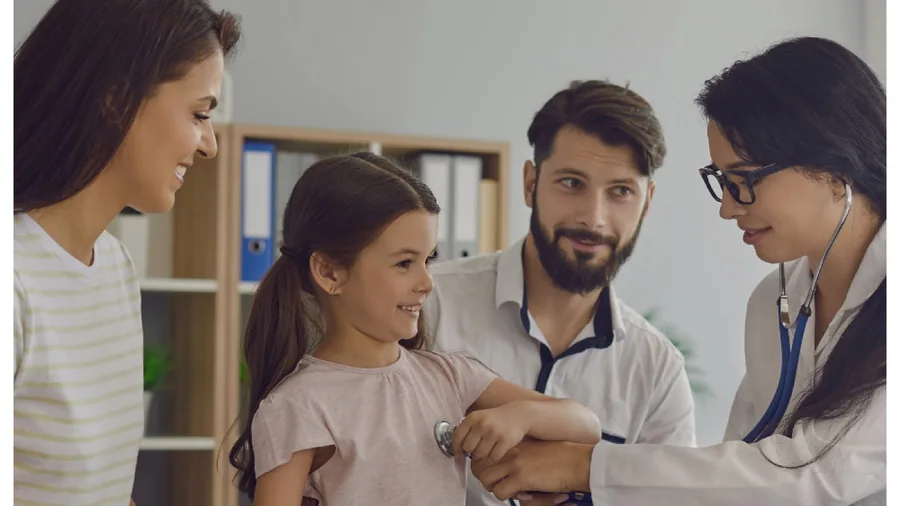 A doctor listening to a child's chest during a family visit